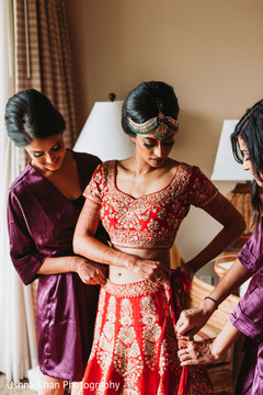 Indian bride being helped to put her lehenga. Indian bride being helped to put her lehenga.