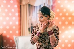Indian bride putting her earrings on. Indian bride putting her earrings on.