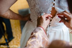 Indian bride getting help to put on her white wedding dress. Indian bride getting help to put on her white wedding dress.