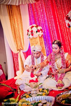 Enchanting Indian couple making offerings to ceremony altar. Enchanting Indian couple making offerings to ceremony altar.
