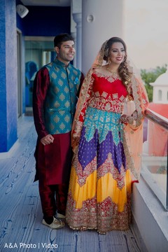 Indian bride and groom posing with their sangeet outfits Indian bride and groom posing with their sangeet outfits