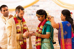 Indian groom putting ring to bride.