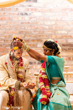 India bride pouring petals and rice onto groom.