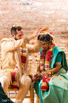 Indian groom pouring rice and petals on bride.