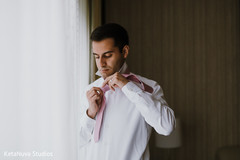 Indian groom putting on his bow tie. Indian groom putting on his bow tie.
