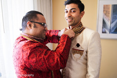 Groom being assisted by groomsman. Groom being assisted by groomsman.