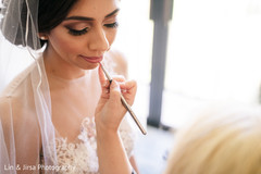 Indian bride being assisted by makeup artist. Indian bride being assisted by makeup artist.