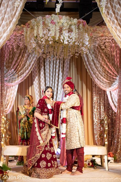 Indian groom putting flower garland to bride