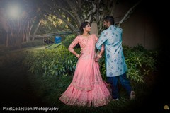 Indian bride and groom posing with their sangeet outfits Indian bride and groom posing with their sangeet outfits