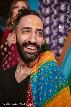 Joyful Indian groom with turmeric paste on his face with rice. Joyful Indian groom with turmeric paste on his face with rice.