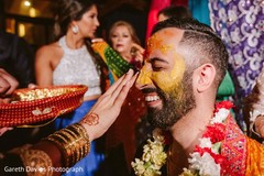 Indian groom being smeared with turmeric paste on his face. Indian groom being smeared with turmeric paste on his face.