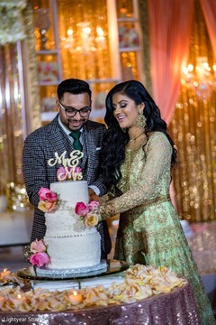 Indian newlyweds cutting the cake during the reception. Indian newlyweds cutting the cake during the reception.