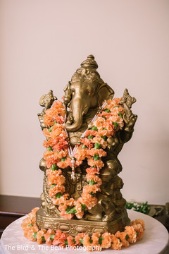Statue of Ganesha decorated with a peach flower garland. Statue of Ganesha decorated with a peach flower garland.