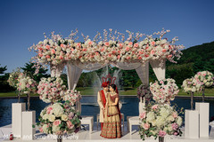 Indian couple posing on the peach and white flowers mandap. Indian couple posing on the peach and white flowers mandap.