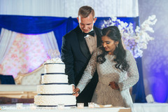 Sweet Indian couple cutting their wedding cake. Sweet Indian couple cutting their wedding cake.