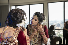 Indian bridal putting her earrings on. Indian bridal putting her earrings on.