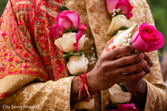 Indian groom holding ornamented coconut and pink rose. Indian groom holding ornamented coconut and pink rose.