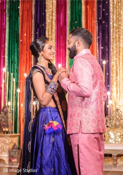 Maharani in blue anarkali with groom in pink nehru jacket.