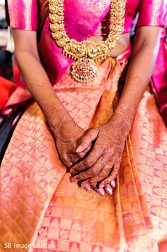 Indian bride with mehndi art on hands wearing golden long necklace. Indian bride with mehndi art on hands wearing golden long necklace.