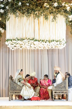 Indian couple seating under the mandap hanging flowers. Indian couple seating under the mandap hanging flowers.