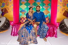 Indian couple in matching blue and gold sitting on stage Indian couple in matching blue and gold sitting on stage