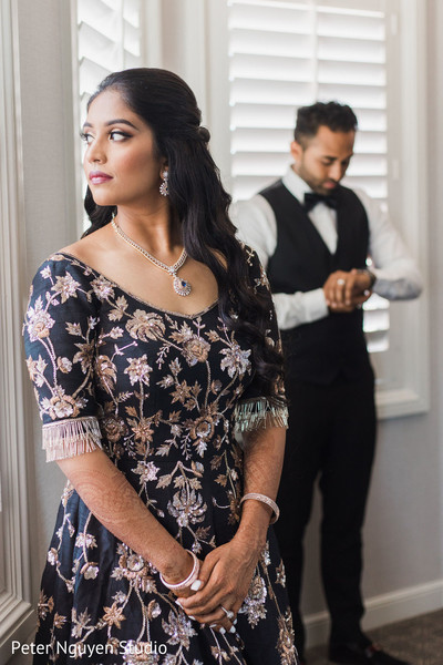 Indian bride looking at the window while groom is putting his watch.