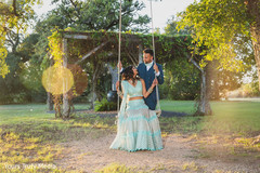 Indian bride looking up to her Indian groom while sitting on a swing Indian bride looking up to her Indian groom while sitting on a swing