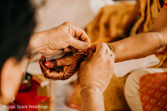 Indian relative tying a thread around the Indian bride's wrist Indian relative tying a thread around the Indian bride's wrist
