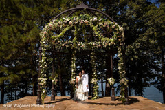 Indian couple posing under flower decorated mandap. Indian couple posing under flower decorated mandap.