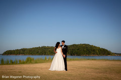 Indian couple posing next to lake on their reception outfits. Indian couple posing next to lake on their reception outfits.