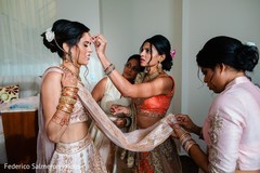 Indian bride being helped with her bridal look. Indian bride being helped with her bridal look.