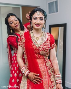 Indian bride on her red and golden lehenga with jewelry on. Indian bride on her red and golden lehenga with jewelry on.