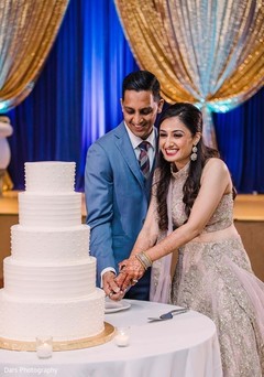 Indian bride and groom cutting white wedding cake. Indian bride and groom cutting white wedding cake.