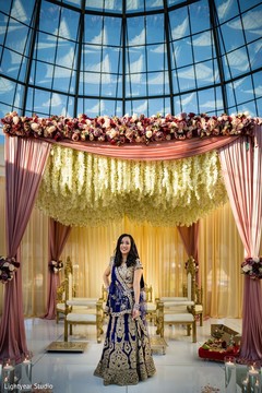 Indian bride posing on her blue lehenga under flower mandap. Indian bride posing on her blue lehenga under flower mandap.