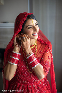 Indian bride putting her earrings on. Indian bride putting her earrings on.
