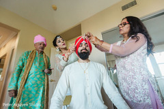Indian groom being helpep on putting his kilangi on. Indian groom being helpep on putting his kilangi on.