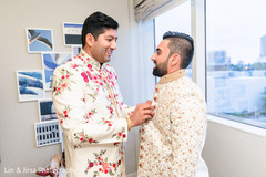 Indian relative helping the Indian groom with his sherwani Indian relative helping the Indian groom with his sherwani