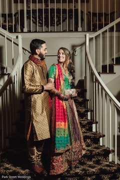 Indian couple posing on their golden, green and red sangeet outfits. Indian couple posing on their golden, green and red sangeet outfits.