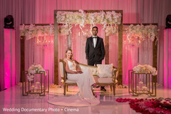 Indian bride and groom posing on reception pink stage. Indian bride and groom posing on reception pink stage.