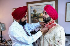Indian relative helping the Indian groom to button his jacket Indian relative helping the Indian groom to button his jacket