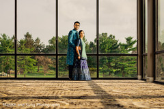 Indian couple posing in front of a window with a view of the forest Indian couple posing in front of a window with a view of the forest