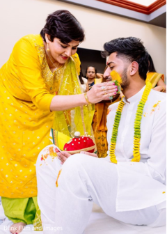 Indian relative applying tumeric paste to the Indian groom's face Indian relative applying tumeric paste to the Indian groom's face