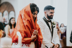 Indian bride wearing her orange ceremony veil next to groom. Indian bride wearing her orange ceremony veil next to groom.