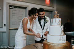 Indian bride and groom cutting white and golden cake. Indian bride and groom cutting white and golden cake.
