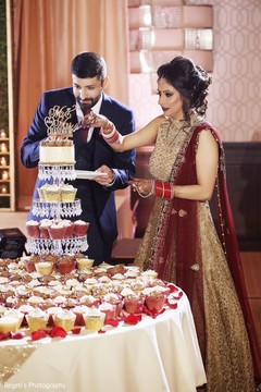 Maharani in golden lengha cutting the cake with her groom. Maharani in golden lengha cutting the cake with her groom.