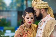 Indian couple posing in their golden, red and peach wedding outfits. Indian couple posing in their golden, red and peach wedding outfits.