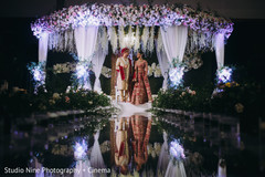 Indian bride and groom posing under ceremony white mandap. Indian bride and groom posing under ceremony white mandap.
