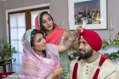 Indian groom getting his Sarpech on red turban. Indian groom getting his Sarpech on red turban.
