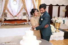 Indian couple next to white wedding cake. Indian couple next to white wedding cake.