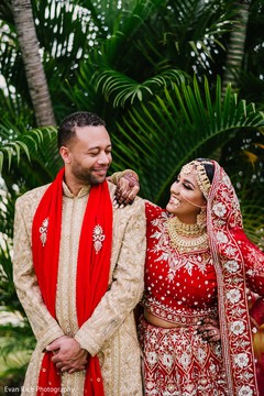 Indian couple posing in their red, and ivory ceremony outfits. Indian couple posing in their red, and ivory ceremony outfits.